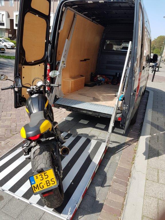 Motorfiets op laadramp in bestelwagen