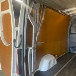 Bestelwageninterieur met laadklepmechanisme.