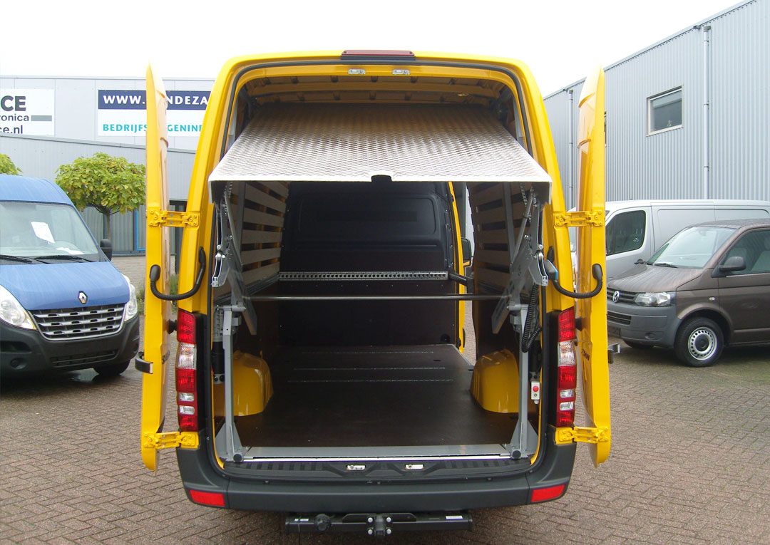 Open laadruimte van gele bestelwagen op parkeerplaats.